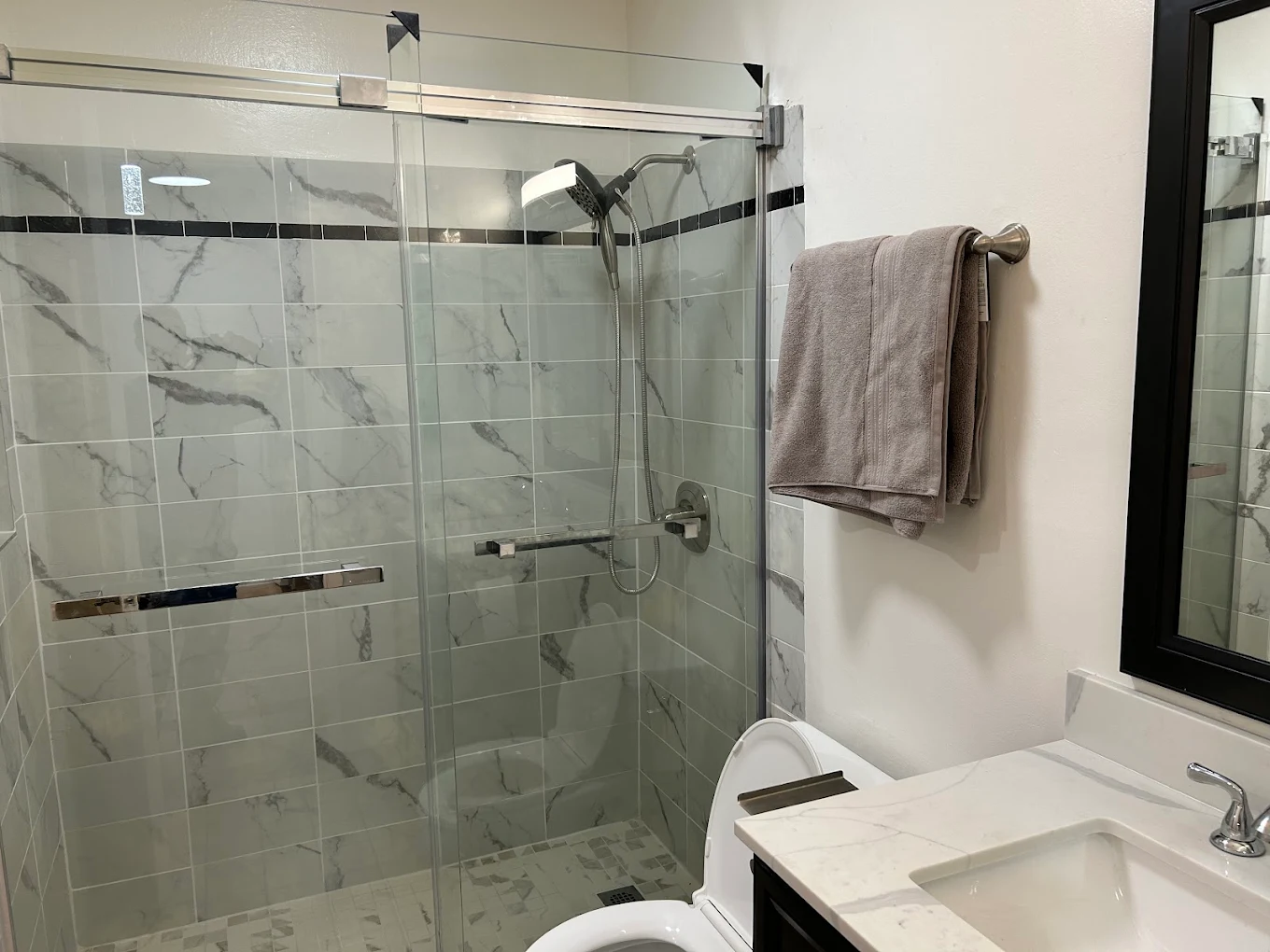 Marble-tile shower with frameless sliding glass